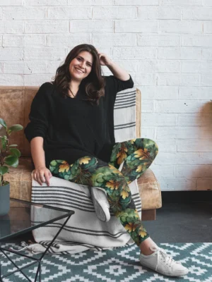 Woman lounging on couch smiling, wearing NCharnt Green and Gold Oak Leaf Leggings Woman lounging on couch smiling, wearing NCharnt Green and Gold Oak Leaf Leggings