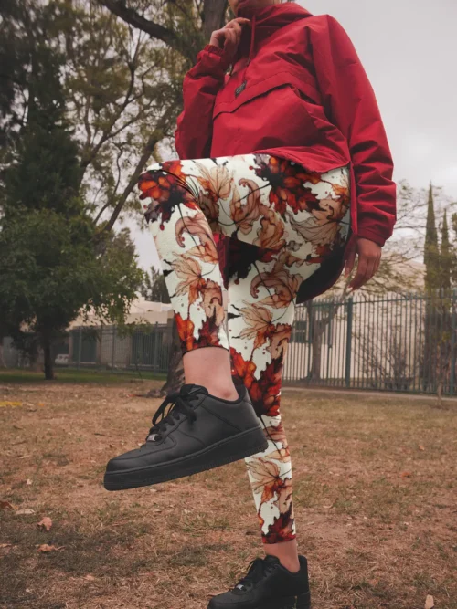 Woman wearing NCharnt Red and orange Maple leaf trendy yoga leggings playfully kicking in park Woman wearing NCharnt Red and orange Maple leaf trendy yoga leggings playfully kicking in park