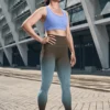 Woman wearing NCharnt sculpting athletic leggings blue and brown ombre with gradient standing in front of a building Woman wearing NCharnt sculpting athletic leggings blue and brown ombre with gradient standing in front of a building