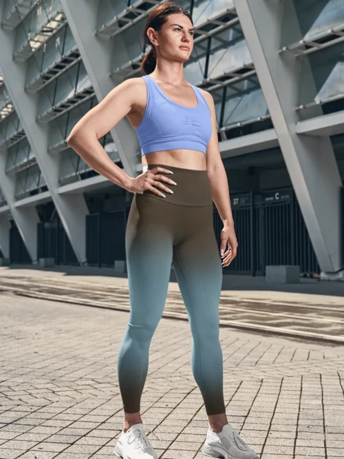 Woman wearing NCharnt sculpting athletic leggings blue and brown ombre with gradient standing in front of a building Woman wearing NCharnt sculpting athletic leggings blue and brown ombre with gradient standing in front of a building